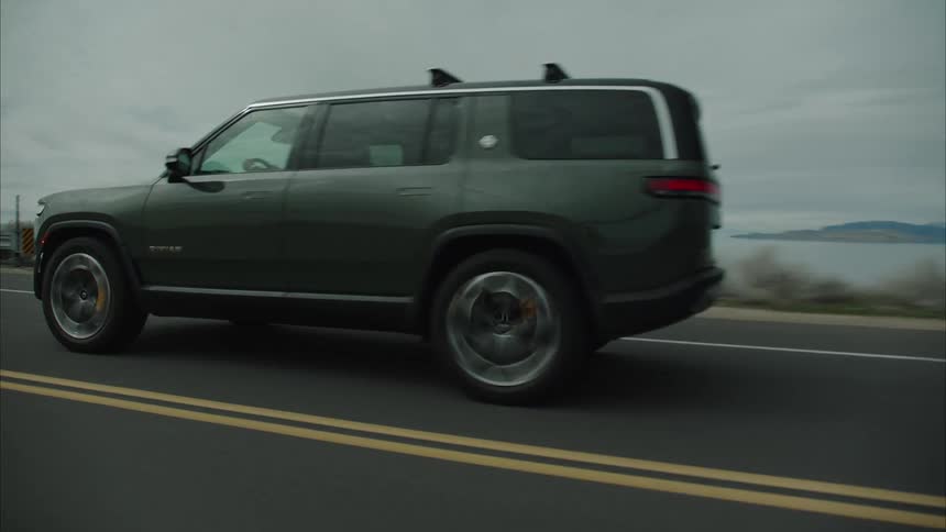 The suv is driving down the road and comes up on another car that is driving the same way