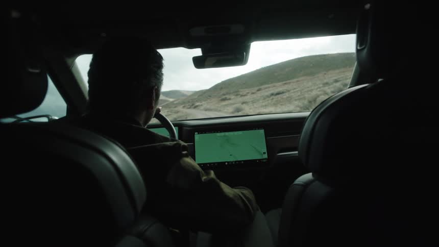 A man leans to his side while driving off road