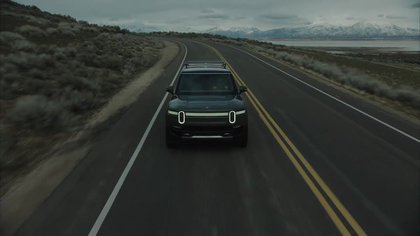 A black suv driving on an asphalt road in a region with flat fields on the sides