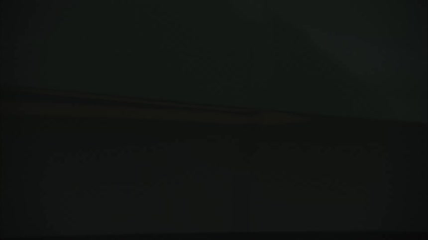 A closeup reveals the door of a moving vehicle with the word rivian displayed set against an overcast sky