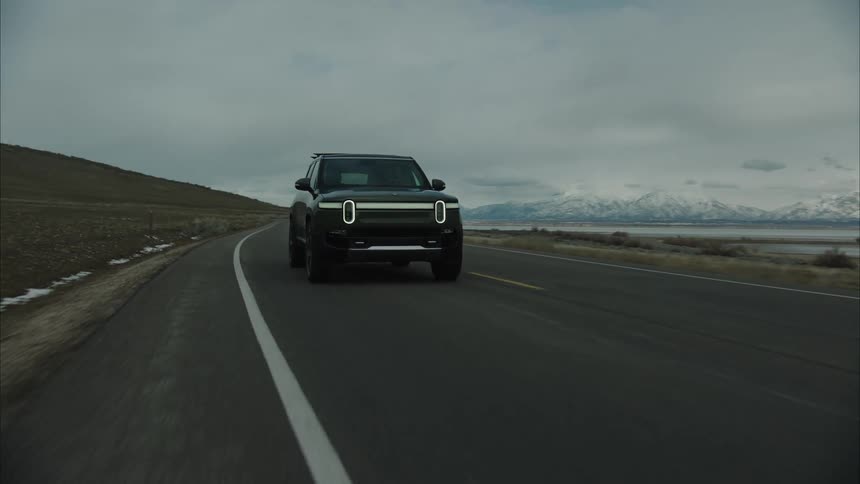A black suv driving in a tarmac road in a rural region