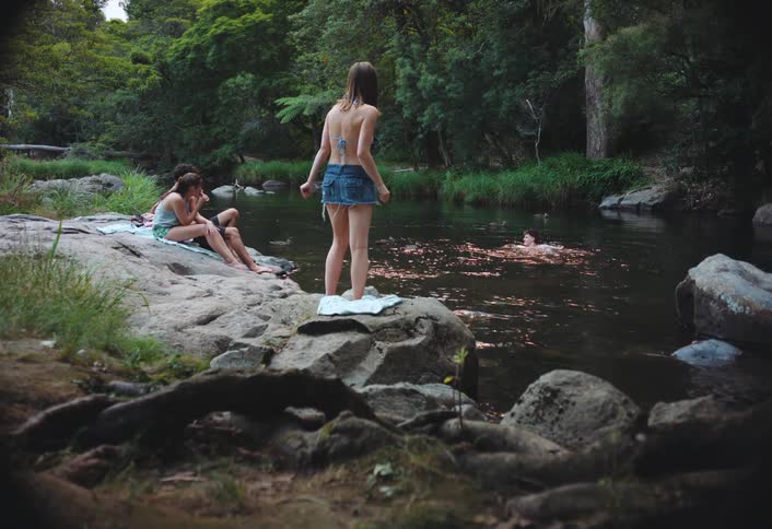Friends hanging out at a swimming hole in the forest
