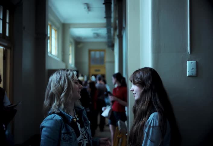 Students talk while others move through the corridor of a school