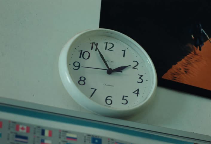 A white clock with its hand spinning fast and hanging on the wall