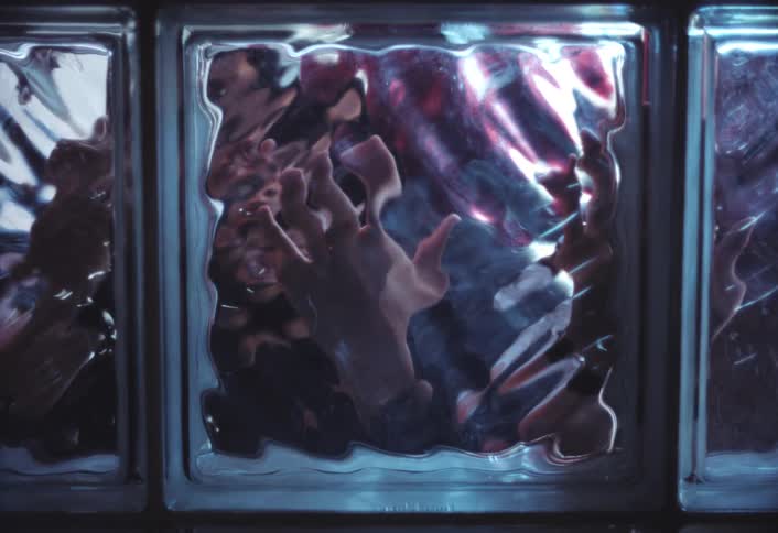 A person looks upset and confused as they knock on a glass block