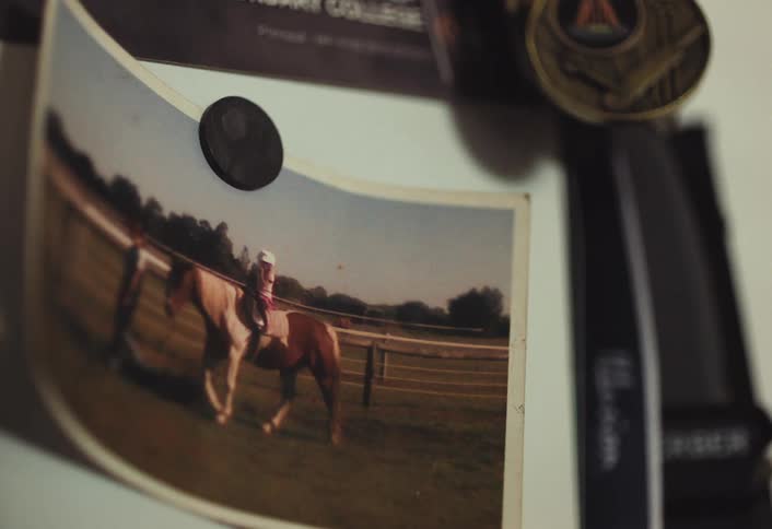 The picture of the girl on the horse being led my a man is hung with a magnet