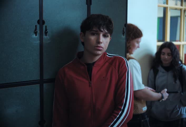 A teenager is leaning against the lockers