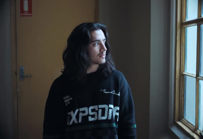 Boy with long hair looking out the window then turns to the camera