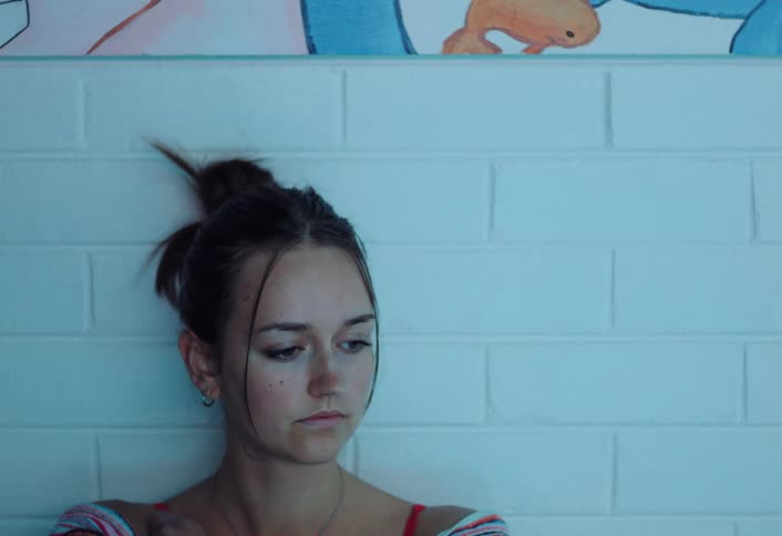 People walk past a teenage girl who looks depressed