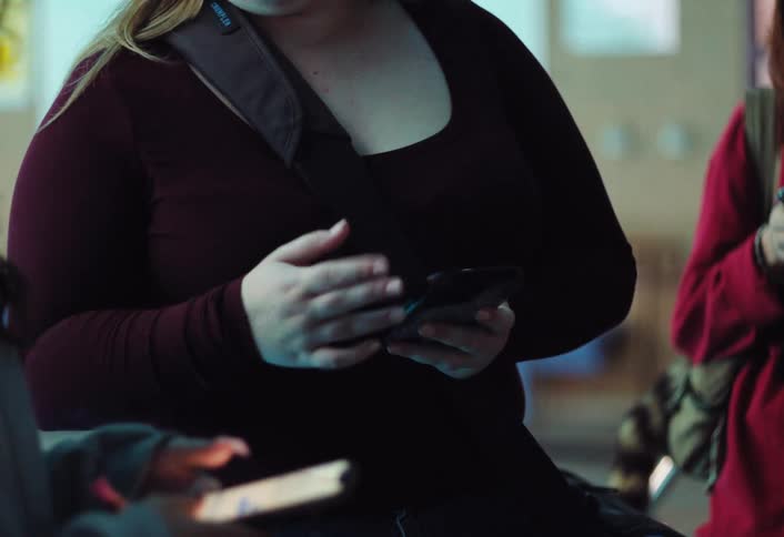 Three women standing together text and move their hands in conversation