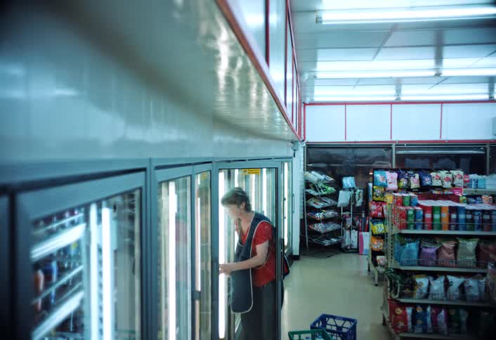 A worker stocks milk then she stands still