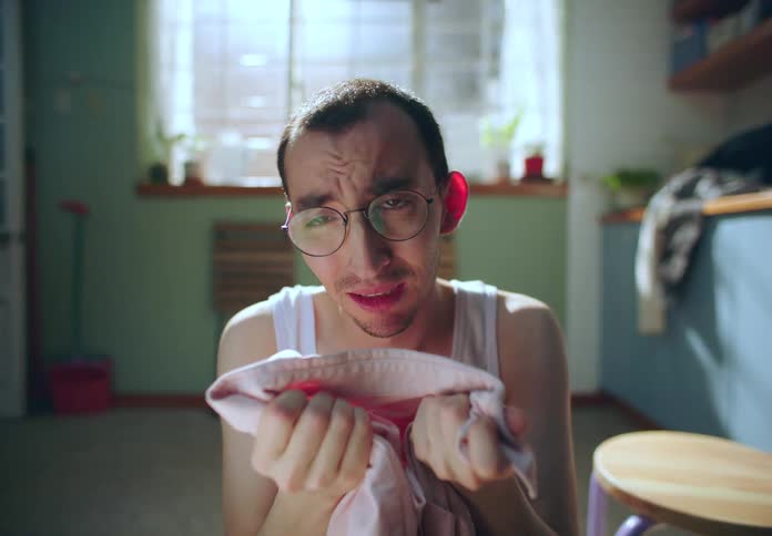 A man anguishes over a shirt stained pink overwhelmed with panic