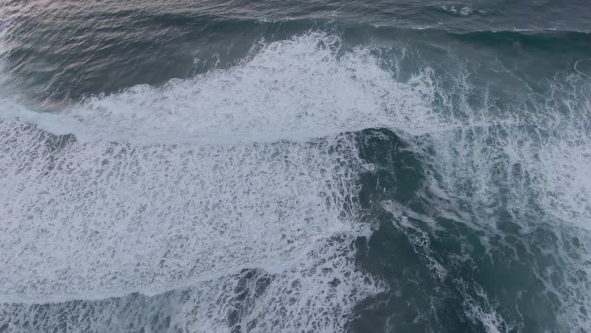 Aerial of ocean waves rolling into a sandy beach