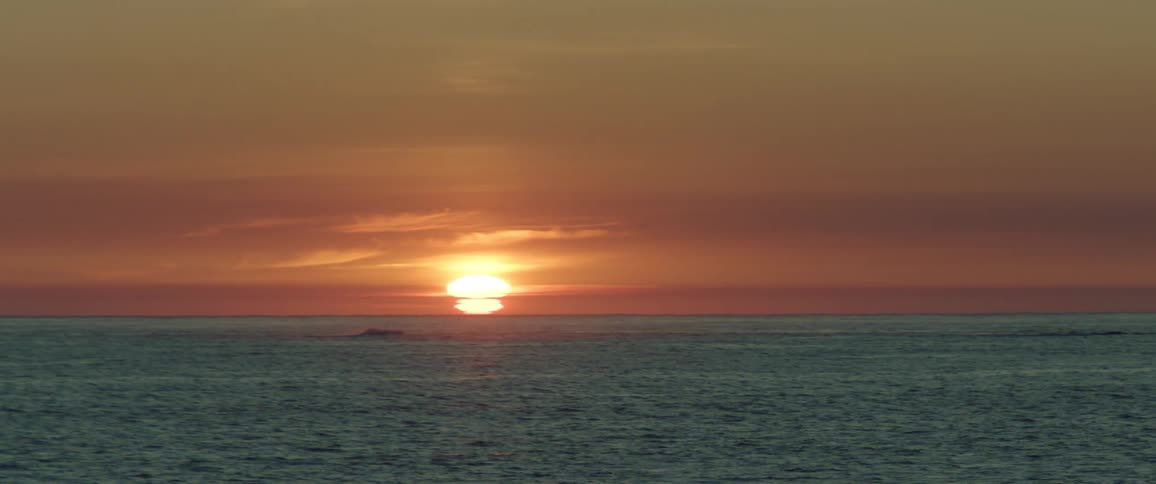 The sun sets on the horizon casting a warm glow over the ocean