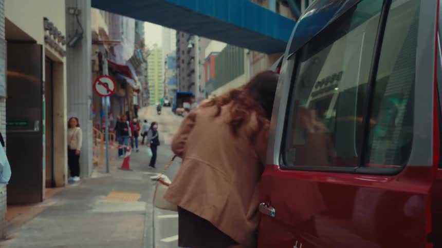 Girl in a skirt gets into a red van in a big busy city