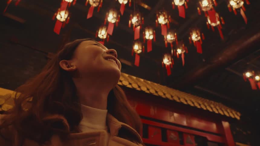 A woman looks up at all the lamps hanging in the shrine
