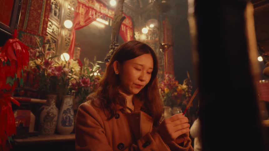A woman is praying at the altar with incense