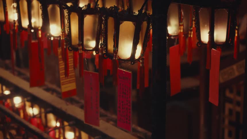 A row of illuminated lanterns with red and yellow tags hangs casting a warm and festive glow