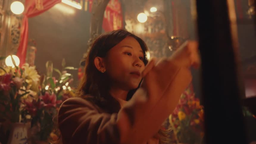 Woman making prayer sign in a temple and holding incense