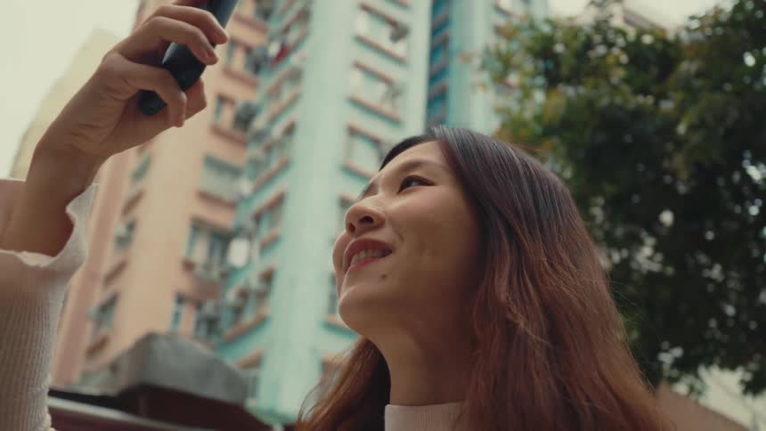 Girl in a city taking cell phone photos and smiling