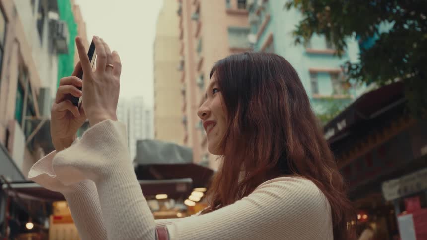Woman in an urban center pointing her smartphone forward