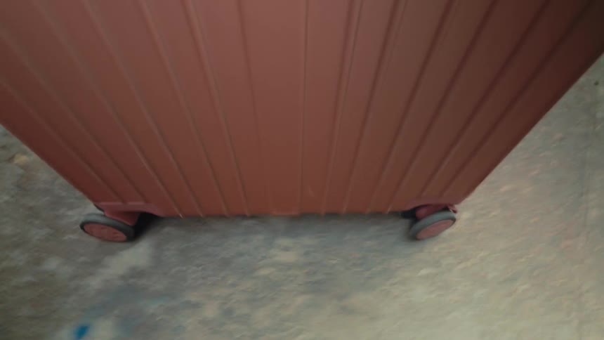 The luggage is rolling on the sidewalk