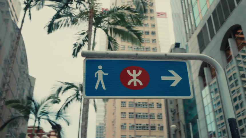 In a lowangle perspective a blue pedestrian guidepost directs towards the right featuring clear human figure representations positioned distinctly amidst towering structures in a vibrant urban setting