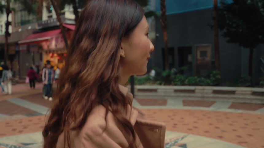 Woman smiles while walking across a crowded plaza during the daytime