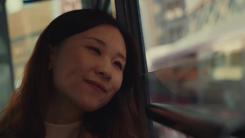 A woman is smiling as she rides in the bus