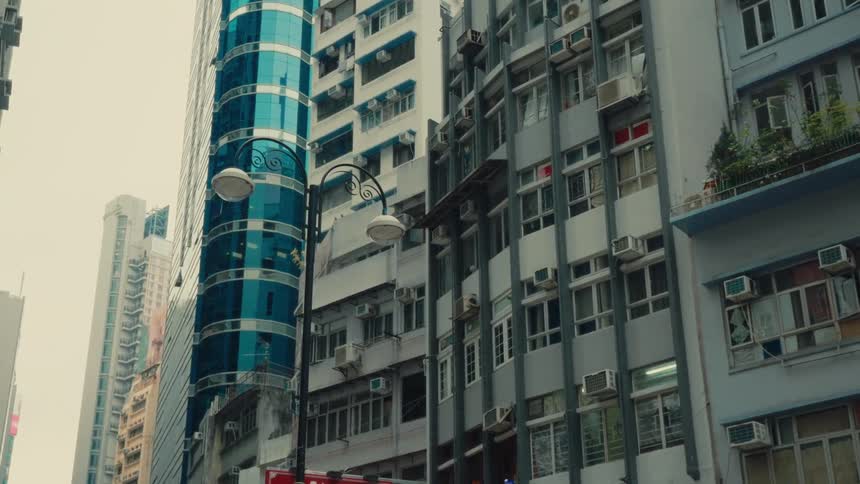 Apartment buildings tower over a streetlight during the day