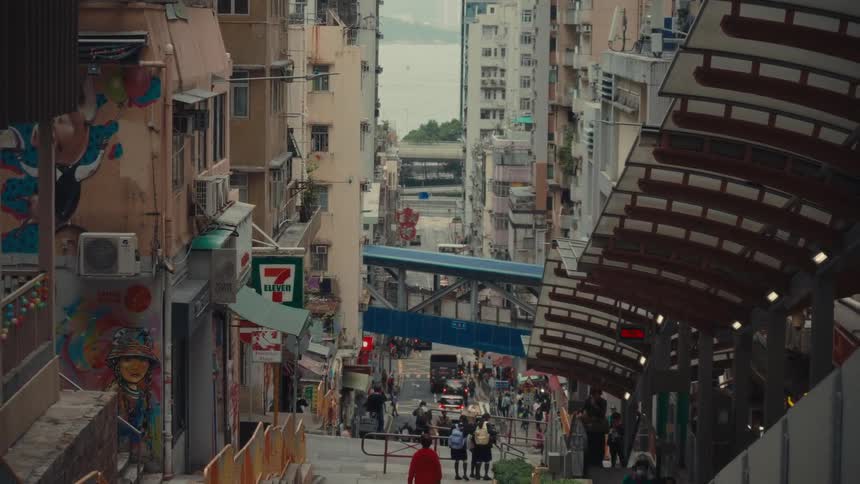 A dynamic urban hong kong view from atop a staircase as it looks downward where people go about thier day schoolchildren traverse the steps while the hustle and bustle of city traffic flows along the street below