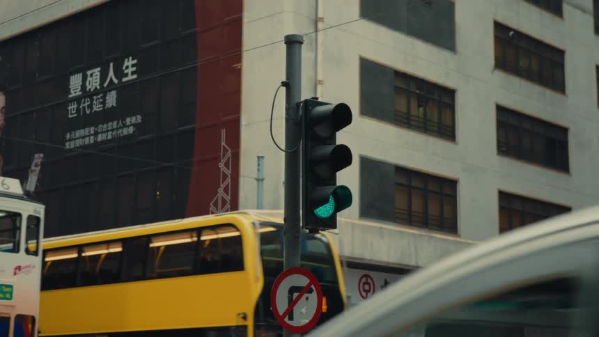 A traffic signal transitions displaying a green as vibrant duallevel buses and typical trams holding passangers proceed forward showing movement on a bustling street