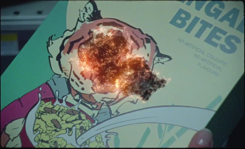 A closeup of a bengal bites cereal box held by a person is zoomed into the box then begins to burn with a hole set a blaze