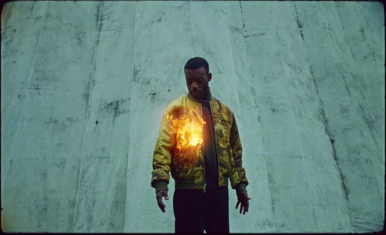 Man looking at the sleeve of his coat after a while it catches fire and he feels satisfied