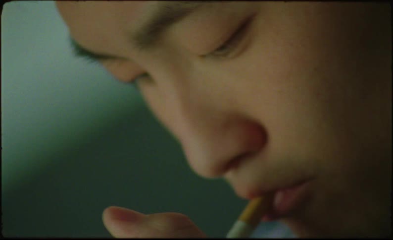 Asian man lighting a cigarette then looking up