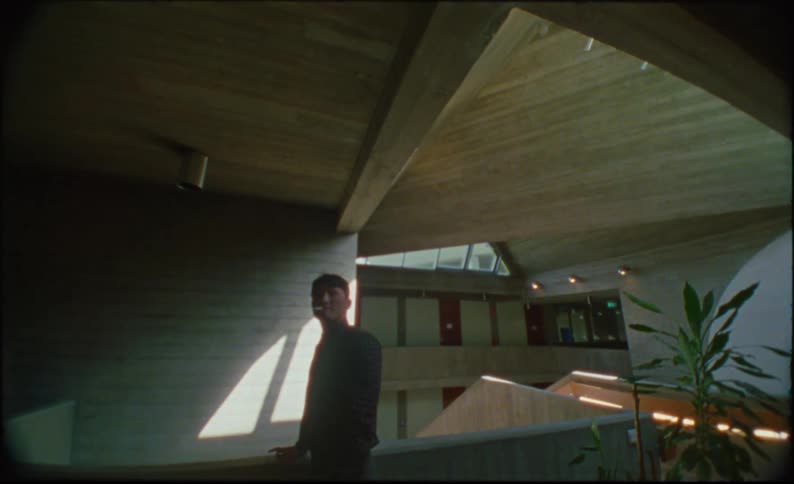 Asian man smoking a cigarette while looking down at a flight of interior stairs then turning hastily