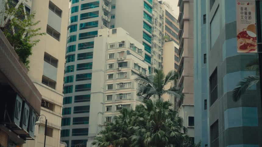 A handheld perspective showcases a dense highrise hong kong architectural view presenting a close and packed composition of different building exteriors and a sign featuring chinese calligraphy