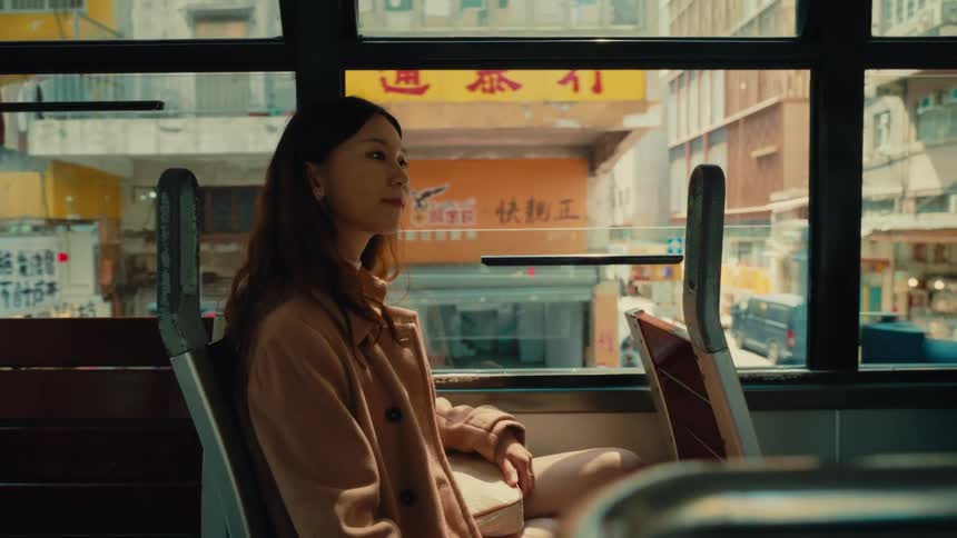 She looks around at the buildings as she rides on the bus