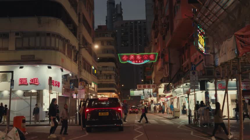 A hong kong street at night showcases urban existence as individuals fill a crosswalk near a stationary van displaying hazard signals amid many neonlit businesses under a dark sky