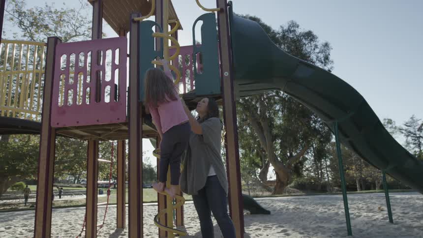 Woman and girl play at playground