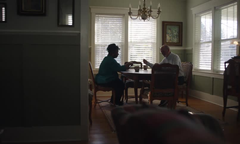 Man and woman play cards while sitting in their dining room during the day