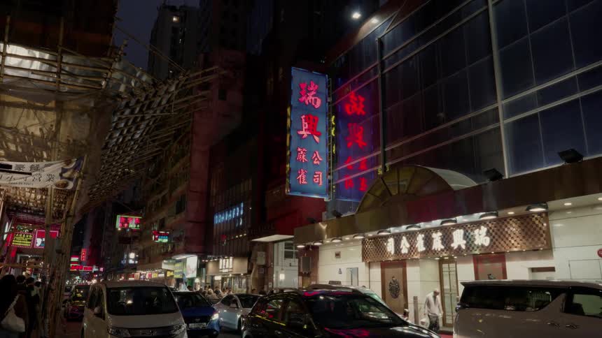People and cars travel past the building at night