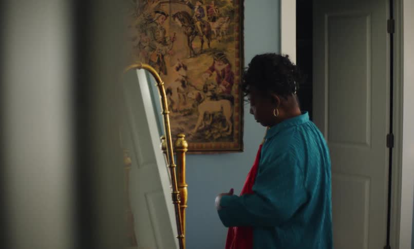 Woman looking at herself in the mirror with an evening gown resting on the front
