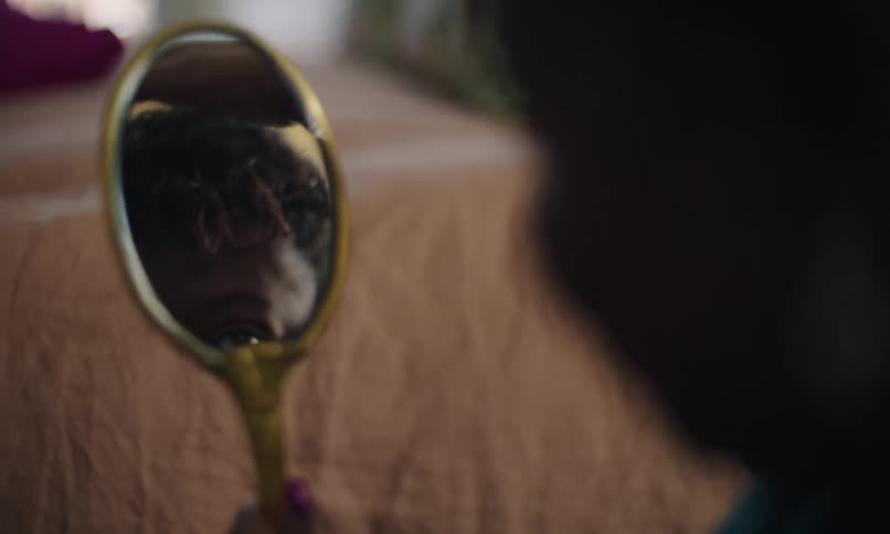 Lady looking in a small mirror and adjusting her hair