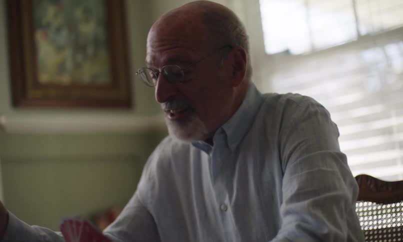 Old man playing cards and talking to someone