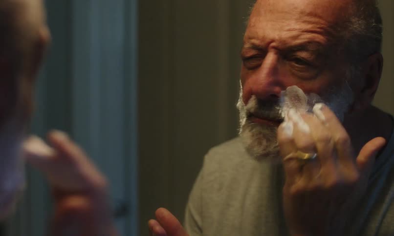 Elderly man putting shaving foam in the mirror