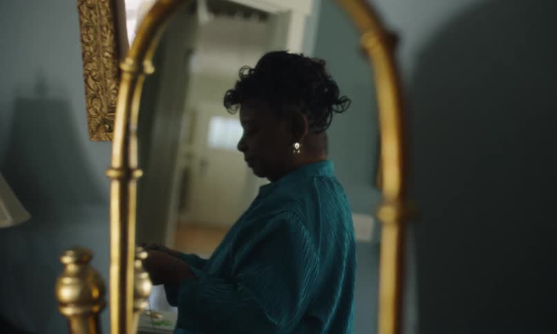 A woman is getting dressed and putting on jewelry in a mirror