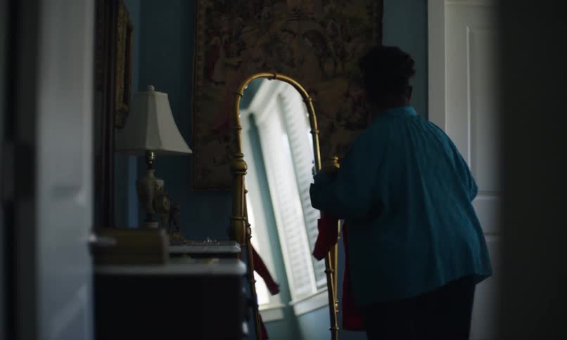 Woman happily approaching a mirror with a dress in her hand