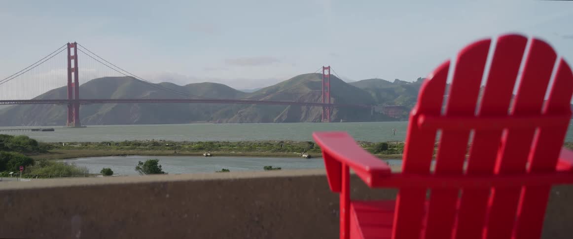A red chair looking out towards a large bridge