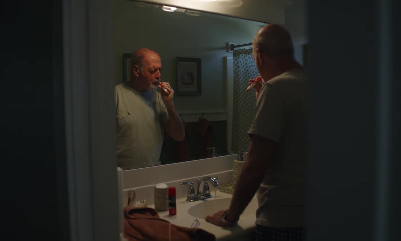 Elderly man brushing his teeth in the bathroom
